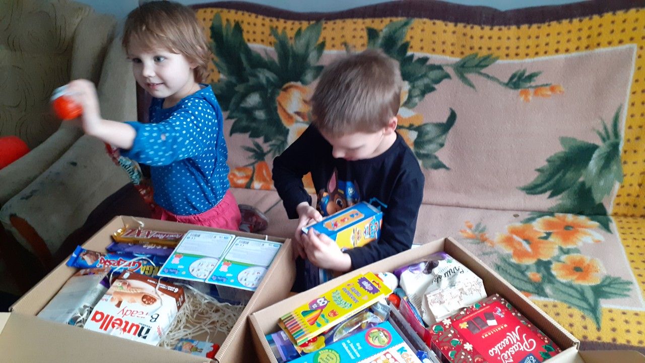 na zdjęciu dzieci rozpakowujące paczki świąteczne